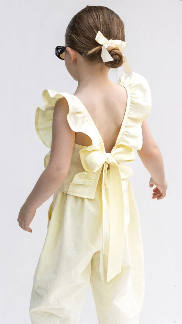Child wearing a ruffle summer top with tie-back straps, shown in a kids sewing pattern listing.