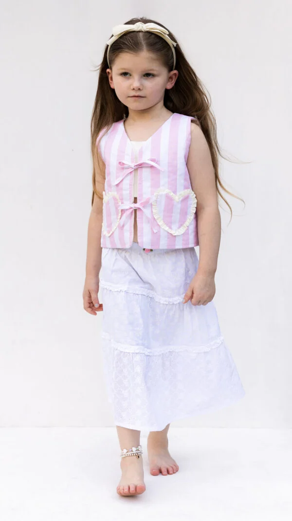Girl wearing quilted vest pattern with oversized bow tie closure and heart pocket
